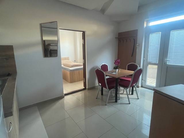 Apartmány na prenájom. - Jedáleň so stolom, stoličkami a izbou. Interiér v neutrálnej farebnosti, svetlá podlaha.