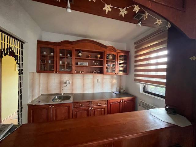 Rodinný  dom na predaj v Gabčíkove - Kuchyňa so skrinkami v rodinnom dome, drevený nábytok a prúžkové žalúzie na okne.