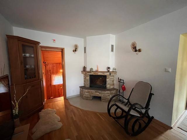 Rodinný  dom na predaj v Gabčíkove - Obývačka so smotanovými stenami a krbom, doplnená o kolísku a drevený nábytok. Rodinný dom.