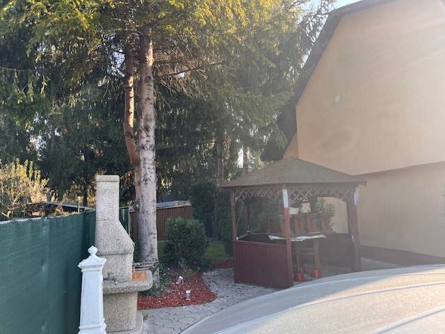 Rodinný  dom na predaj v Gabčíkove - Rodinný dom obklopený stromami, altánkom a kamenným krbom v záhrade.