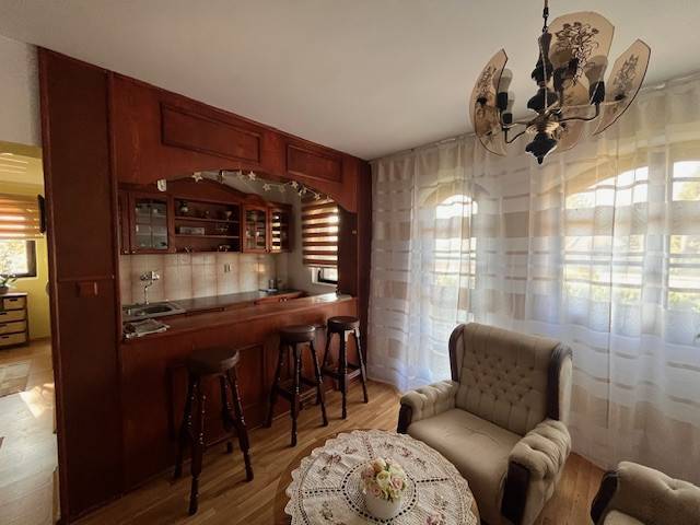 Rodinný  dom na predaj v Gabčíkove - Obývačka rodinného domu s dreveným barom a pohodlnými kreslami, presvetlené záclonami.