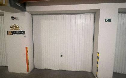 Garáž na prenájom. - Garáž v interiéri s bielymi dverami a bezpečnostnými značkami.