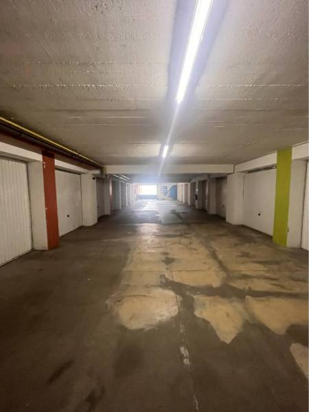Garáž na prenájom. - Interiér garáží s osvetlením a betónovou podlahou.