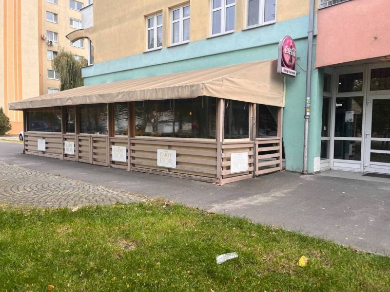 Znížená cena!!!!   Obchodný priestor na predaj. - Exteriér obchodných priestorov v Dunajskej Strede, s reštauračnou terasou a zelenou trávou.