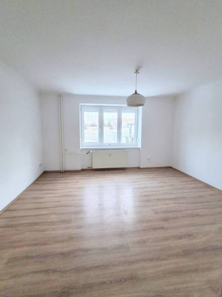 ☎️   0918 846 340           Byt v centre mesta na Jesenského ulici. - Priestranná izba s podlahou s dreveným dekorom v 1-izbovom byte, okno a svetlo.