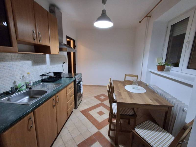 ☎️   0918 846 340           Byt v centre mesta na Jesenského ulici. - Kuchyňa v 1-izbovom byte so štvorcovými dlaždicami a dreveným dekorom na nábytku.