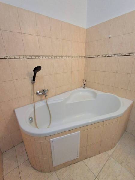 ☎️   0918 846 340           Byt v centre mesta na Jesenského ulici. - Rohová vaňa s béžovými obkladačkami v 1-izbovom byte, neutrálny dizajn.