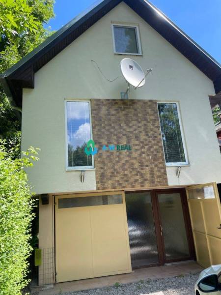 Odstúpenie nájomnej zmluvy - rekreačná chata v obci Bodíky!!! Cena  84 - Zobrazená je budova s anténou, veľkými oknami, zeleným okolím a vstupom do domu.