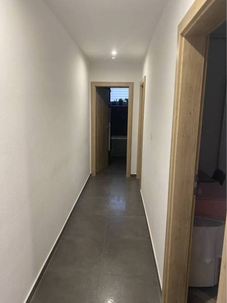 Na predaj: 3-izbový rodinný dom na predaj v obci Lesné Kračany - Úzka chodba rodinného domu s bielymi stenami a dlažbou, osvetlená bodovým svetlom.