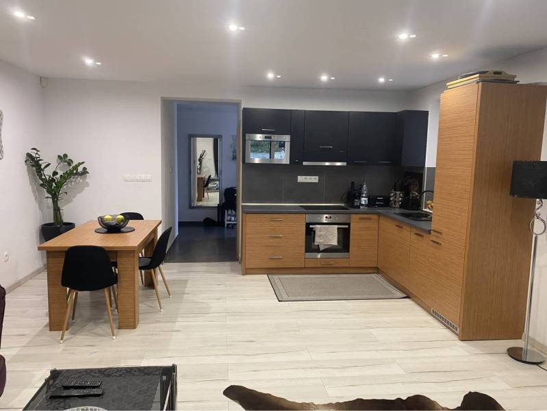 Na predaj: 3-izbový rodinný dom na predaj v obci Lesné Kračany - Kuchyňa v rodinnom dome s čiernou a drevenou kuchynskou linkou a pohovkou.