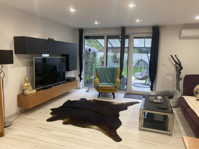 Na predaj: 3-izbový rodinný dom na predaj v obci Lesné Kračany - Obývacia izba v rodinnom dome s televízorom, dekorom Buddhu a terasovým výhľadom.