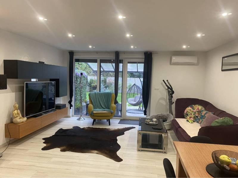 Na predaj: 3-izbový rodinný dom na predaj v obci Lesné Kračany - Obývacia izba s televízorom, pohovkou a podlahou s dreveným dekorom v rodinnom dome.