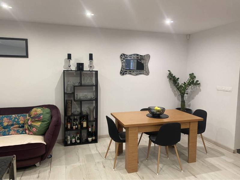 Na predaj: 3-izbový rodinný dom na predaj v obci Lesné Kračany - Obývacia izba v rodinnom dome s podlahou s dreveným dekorom, stolom, pohovkou a rastlinou.