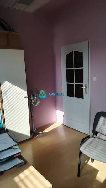 Kancelársky priestor s klimatizáciou na prenájom - Kancelárie s fialovými stenami, stolným ventilátorom a časťou kancelárskeho nábytku na ulici.