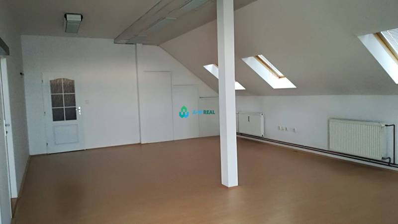 Kancelársky priestor na prenájom v Dunajskej Strede - Podkrovná kancelária s drevenou podlahou, strešnými oknami a bielymi stenami na ulici neuvedené.