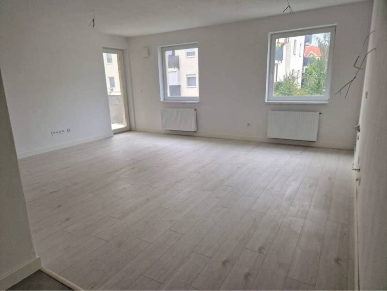 NOVOSTAVBA! Krásny, moderný a priestranný 3-izbový byt s veľkou logiou - Svetlý obývací priestor s podlahou s dreveným dekorom v 3-izbovom byte.