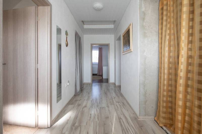 Dvojpodlažný rodinný dom s veľkým pozemkom na predaj v obci Jahodná - Chodba so svetlým dreveným obkladom, závesmi na stene Rodinného domu, na ulici neuvedená.