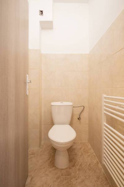 Dvojpodlažný rodinný dom s veľkým pozemkom na predaj v obci Jahodná - Toaleta v rodinnom dome s béžovým obkladom a bielym radiátorom.