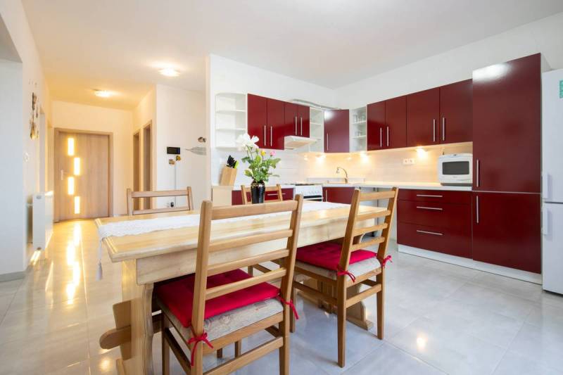 Dvojpodlažný rodinný dom s veľkým pozemkom na predaj v obci Jahodná - Kuchyňa s červenými skrinkami a jedálenským stolom v rodinnom dome.