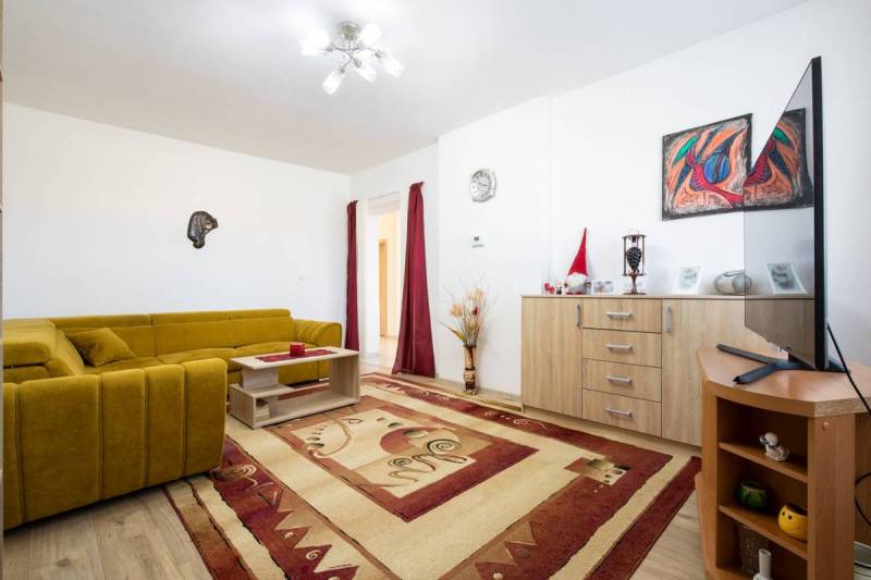 Dvojpodlažný rodinný dom s veľkým pozemkom na predaj v obci Jahodná - Obývacia izba s horčicovou sedačkou, drevenou komodou a televízorom v rodinnom dome.