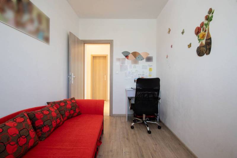 Dvojpodlažný rodinný dom s veľkým pozemkom na predaj v obci Jahodná - Útulná miestnosť s červenou pohovkou, stolom, čiernou stoličkou v rodinnom dome.