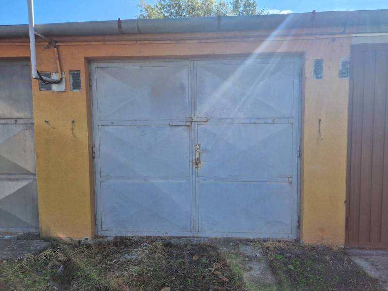 REZERVOVANÉ! Murovaná garáž - Zatvorené garážové dvere, fasáda a trávnatá plocha v Dunajskej Strede.