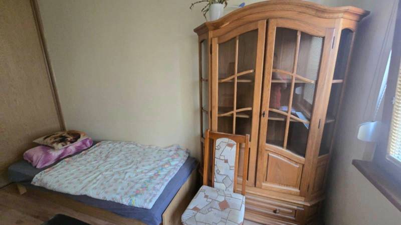 Na prenájom 3-izbový zariadený byt - Dunajská Streda - Izba v 3-izbovom byte s posteľou, skriňou a stoličkou, podlaha s dreveným dekorom.