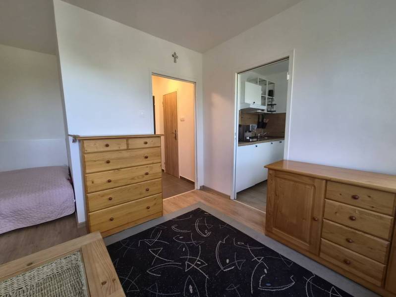 REZERVOVANÉ! Zariadená garsónka po kompletnej rekonštrukcii - Rekreačný apartmán s dreveným nábytkom, podlahou s dreveným dekorom a kuchynským kútom.