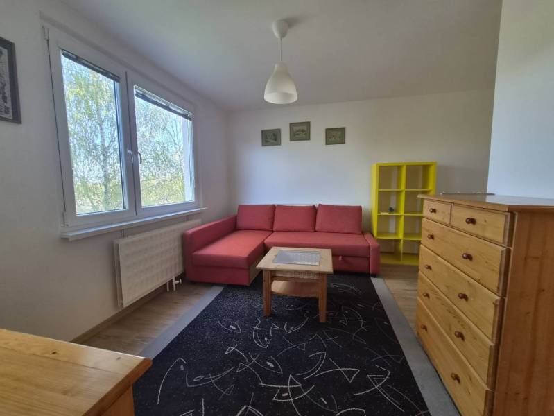 REZERVOVANÉ! Zariadená garsónka po kompletnej rekonštrukcii - Obývacia izba Rekreačného apartmánu s červenou pohovkou, žltou policou a podlahou s dreveným dekorom.