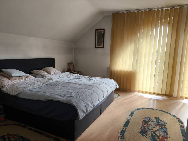 EXKLUZÍVNE LEN U NÁS! - Veľký rodinný dom - Dunajská Streda - Spálňa v rodinnom dome s posteľou, jemnými závesmi a podlahou s dreveným dekorom.