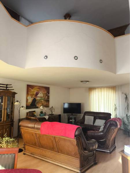 EXKLUZÍVNE LEN U NÁS! - Veľký rodinný dom - Dunajská Streda - Obývacia izba v rodinnom dome s koženou sedačkou a podlahou s dreveným dekorom.