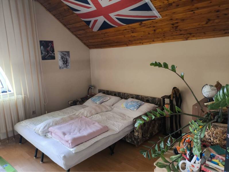 EXKLUZÍVNE LEN U NÁS! - Veľký rodinný dom - Dunajská Streda - Spálňa v rodinnom dome s posteľou, plagátmi a rastlinou, podlaha s dreveným dekorom.