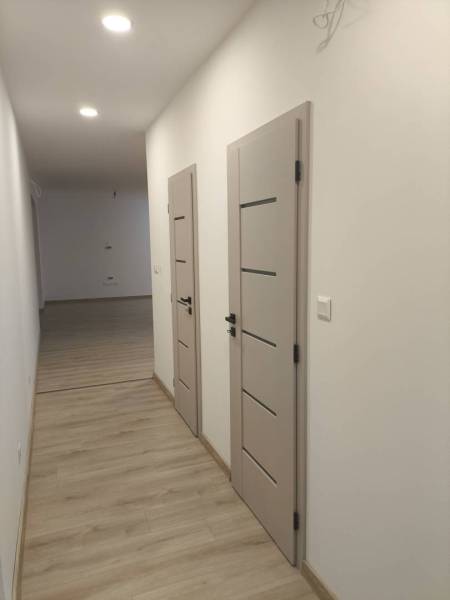 Rezervované / 4-izbový rodinný dom v obci Michal na Ostrove - Chodba s podlahou s dreveným dekorom a dverami v rodinnom dome.