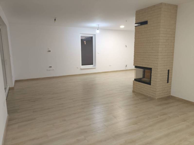 Rezervované / 4-izbový rodinný dom v obci Michal na Ostrove - Obývacia izba s krbom a podlahou s dreveným dekorom v rodinnom dome.