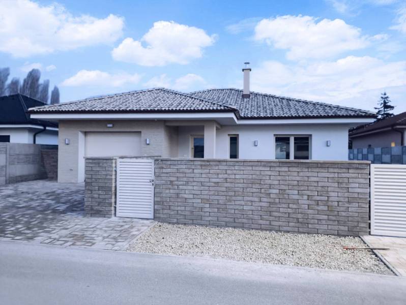 Rezervované / 4-izbový rodinný dom v obci Michal na Ostrove - Rodinný dom v Michal na Ostrove so strechou a plotom z tehál.