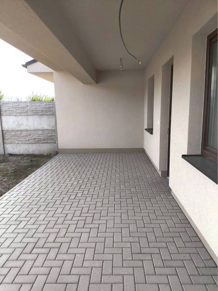 Predané - 4izbový rodinný dom (dvojdom) v obci Horná Potôň! - Vonkajšia terasa rodinného domu v Hornej Potôni s dlažbou a stenou z betónových tvárnic.