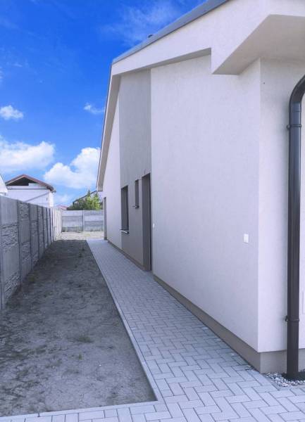 Predané - 4izbový rodinný dom (dvojdom) v obci Horná Potôň! - Bočný pohľad na rodinný dom v Hornej Potôni so spevnenou cestou a plotom.