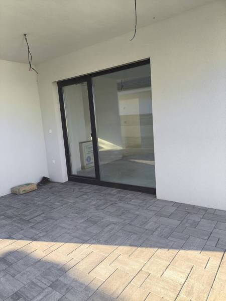 4 izbový rodinný  dom v obci Michal na Ostrove! - Terasa rodinného domu v Michale na Ostrove s veľkými presklenými dverami a dlažbou.