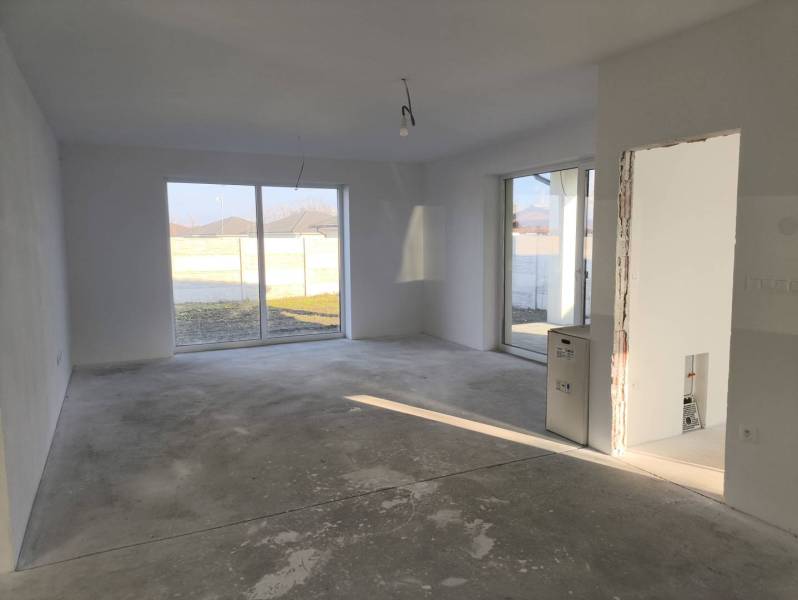 4 izbový rodinný  dom v obci Michal na Ostrove! - Interiér rodinného domu s veľkými oknami a betónovou podlahou.