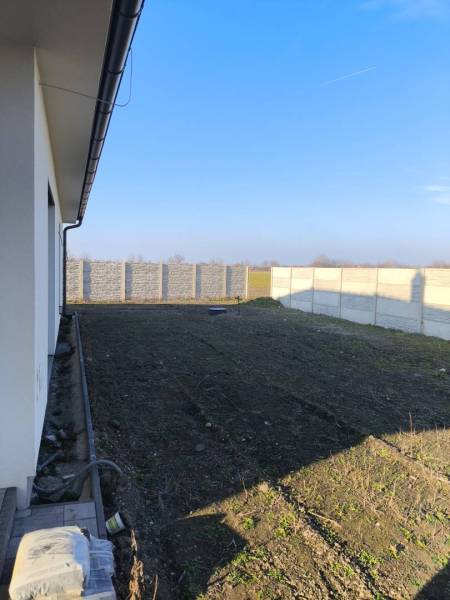 4 izbový rodinný  dom v obci Michal na Ostrove! - Pohľad na bočnú záhradu rodinného domu v Michale na Ostrove s oplotením.