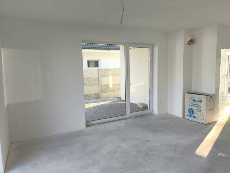 4 izbový rodinný  dom v obci Michal na Ostrove! - Izba s výhľadom na terasu, bielymi stenami a betónovou podlahou v rodinnom dome.