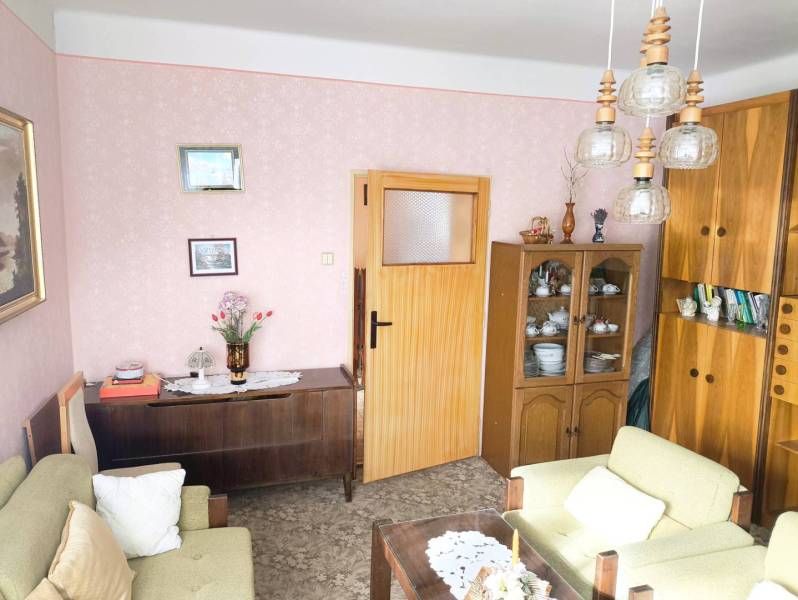 Ponúkame Vám na predaj rodinný dom v obci Horná Potôň - Obývacia izba v rodinnom dome s retro nábytkom a jemným ružovým vzorom tapety.