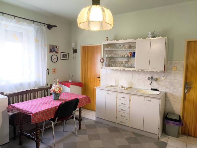 Ponúkame Vám na predaj rodinný dom v obci Horná Potôň - Jedáleň v rodinnom dome s bielou kuchynskou linkou a dreveným stolom.
