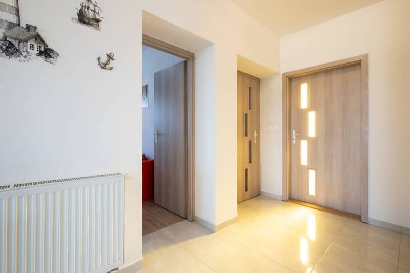 Znížená cena za 4 izbový rodinný dom v obci Jahodná - Chodba rodinného domu s drevenými dverami, radiátorom a stenovými dekoráciami.