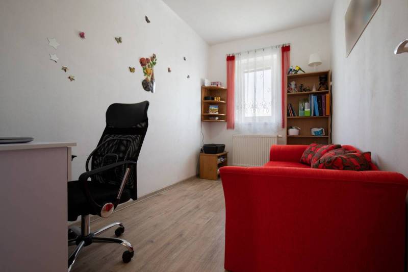 Znížená cena za 4 izbový rodinný dom v obci Jahodná - Interiér pracovne, pohodlná stolička, červený gauč, dekorácie, rodinný dom.