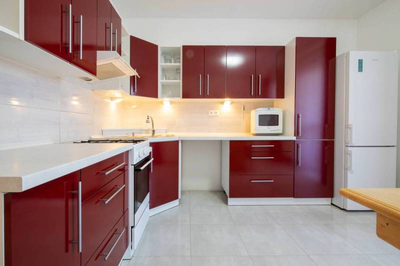 Znížená cena za 4 izbový rodinný dom v obci Jahodná - Kuchyňa v rodinnom dome s červenými skrinkami a bielymi spotrebičmi.