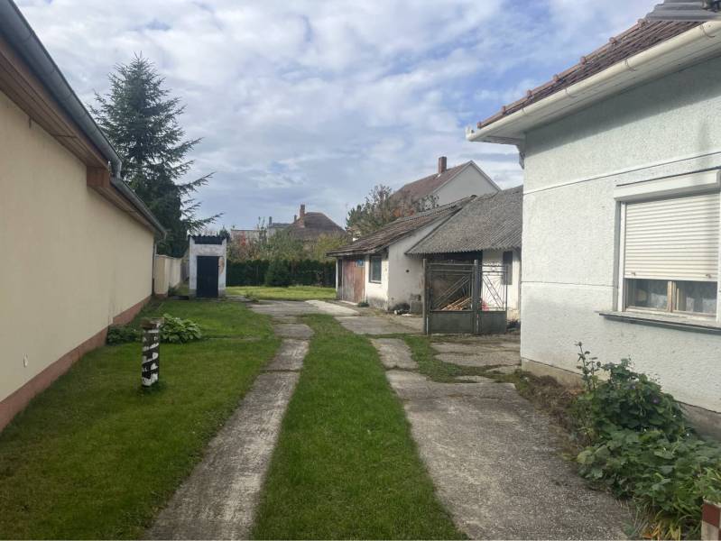 Znížená Cena!Na predaj rodinný dom vo Vrakúni, blízko Dunajskej Stredy - Dvor rodinného domu vo Vrakúni s trávnikom a vonkajšími prístavbami.