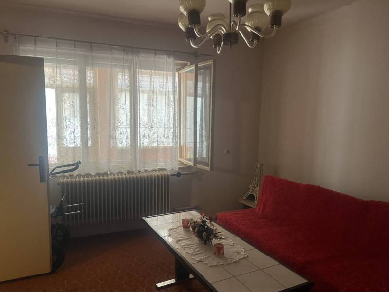 Znížená Cena!Na predaj rodinný dom vo Vrakúni, blízko Dunajskej Stredy - Obývacia izba v rodinnom dome s červenou sedačkou a otvoreným oknom.