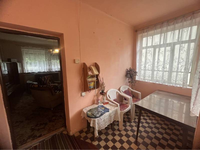 Znížená Cena!Na predaj rodinný dom vo Vrakúni, blízko Dunajskej Stredy - Interiér rodinného domu so stolom, plastovými stoličkami a závesmi na okne.