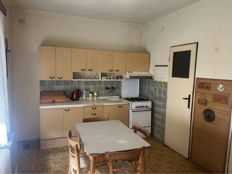 Znížená Cena!Na predaj rodinný dom vo Vrakúni, blízko Dunajskej Stredy - Kuchyňa v rodinnom dome s retro nábytkom a stoličkami, podlaha s dreveným dekorom.